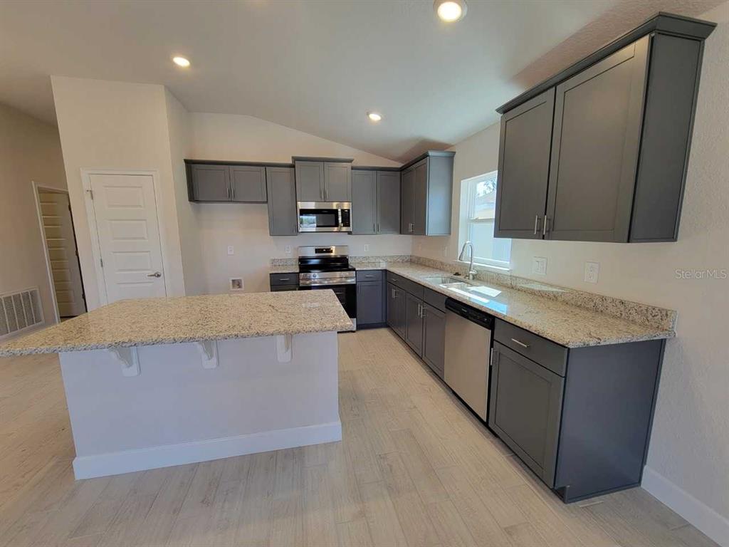 4537 Southwest 91st Ln Road Ocala, FL 34476 - Photo 5 of 18 a large kitchen with stainless steel appliances a sink a stove and a refrigerator