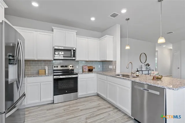 a kitchen with a sink white cabinets and stainless steel appliances
