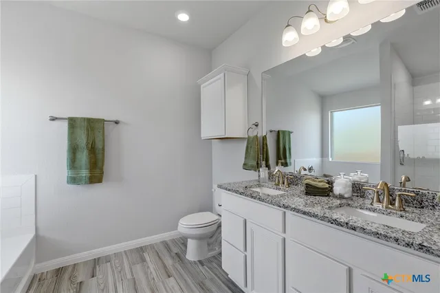 a bathroom with a granite countertop sink a toilet and a mirror