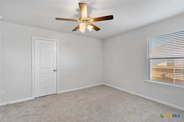 an empty room with a window and a ceiling fan