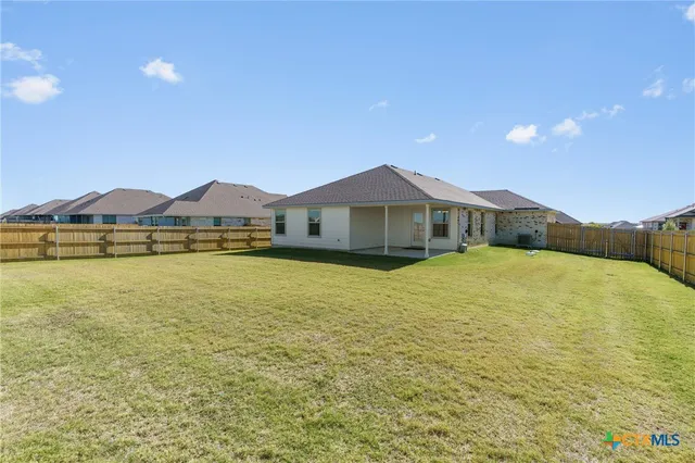 a view of an empty room with kitchen view