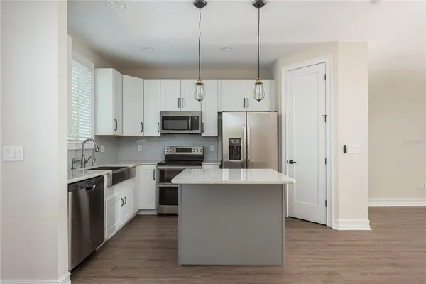 a kitchen with stainless steel appliances a stove a sink a refrigerator a center island and cabinets