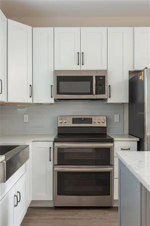 a kitchen with granite countertop white cabinets and stainless steel appliances