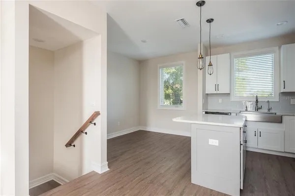 a kitchen with kitchen island a sink wooden floor and a window