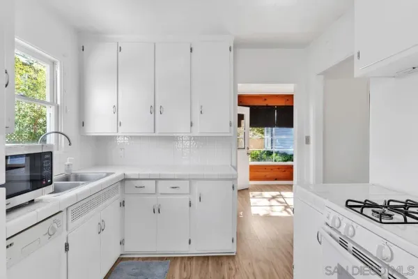 a kitchen with white cabinets and appliances