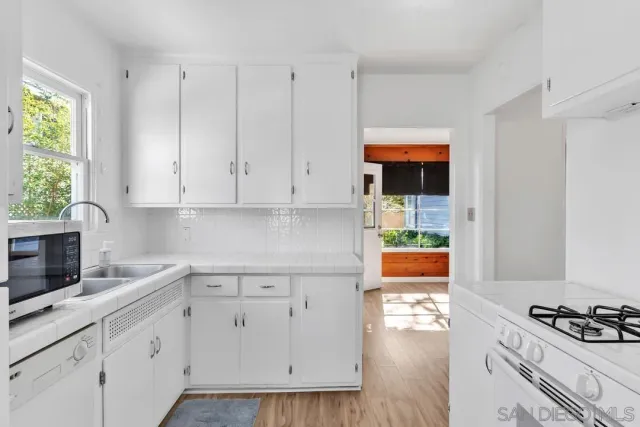 a kitchen with white cabinets and appliances