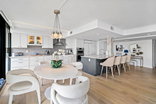 a kitchen with kitchen island granite countertop a dining table chairs and white cabinets