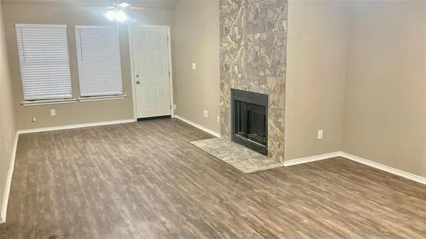 a view of an empty room with wooden floor and a fireplace