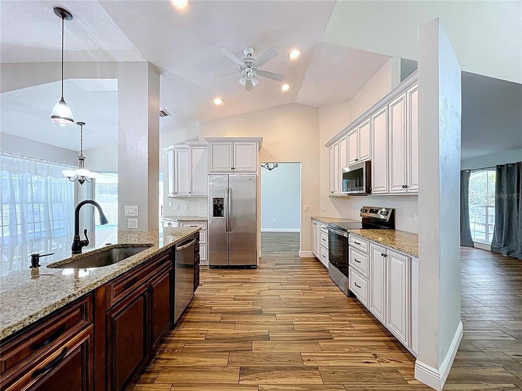 18812 Bascomb Lane Hudson, FL 34667 - Photo 32 of 57 a large kitchen with stainless steel appliances lots of counter space and wooden floor