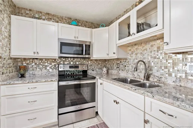a kitchen with granite countertop white cabinets sink and stainless steel appliances