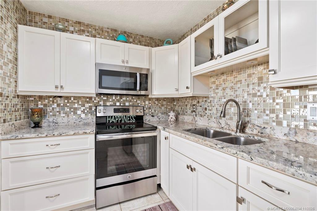 2929 Southeast Ocean Boulevard, Unit 1397 Stuart, FL 34996 - Photo 12 of 38 a kitchen with granite countertop white cabinets sink and stainless steel appliances