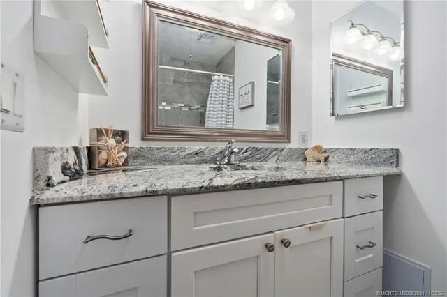 a bathroom with a granite countertop sink vanity and mirror