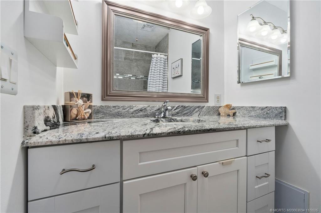 2929 Southeast Ocean Boulevard, Unit 1397 Stuart, FL 34996 - Photo 18 of 38 a bathroom with a granite countertop sink vanity and mirror