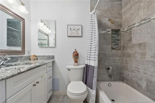 a bathroom with a granite countertop toilet a sink and a bathtub