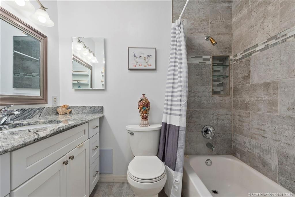 2929 Southeast Ocean Boulevard, Unit 1397 Stuart, FL 34996 - Photo 23 of 38 a bathroom with a granite countertop toilet a sink and a bathtub