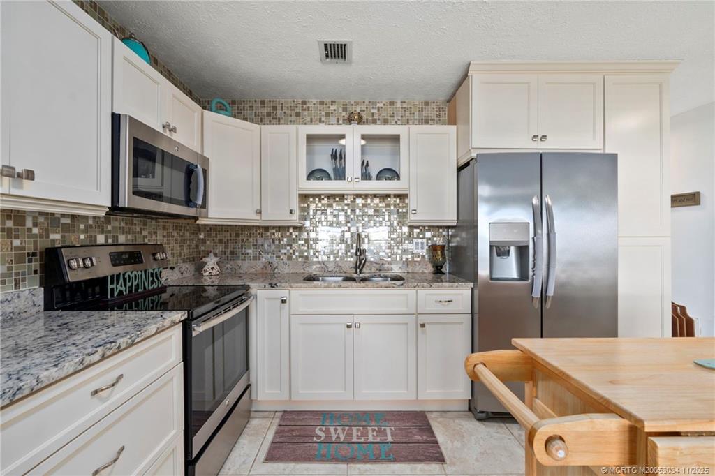 2929 Southeast Ocean Boulevard, Unit 1397 Stuart, FL 34996 - Photo 10 of 38 a kitchen with stainless steel appliances granite countertop a sink stove and refrigerator
