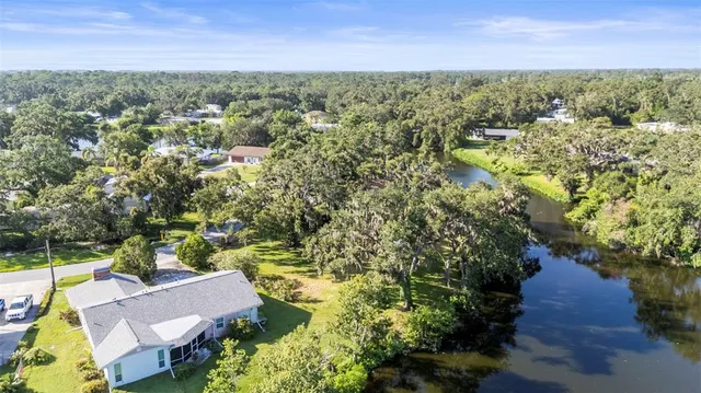 an aerial view of residential house with outdoor space and trees all around