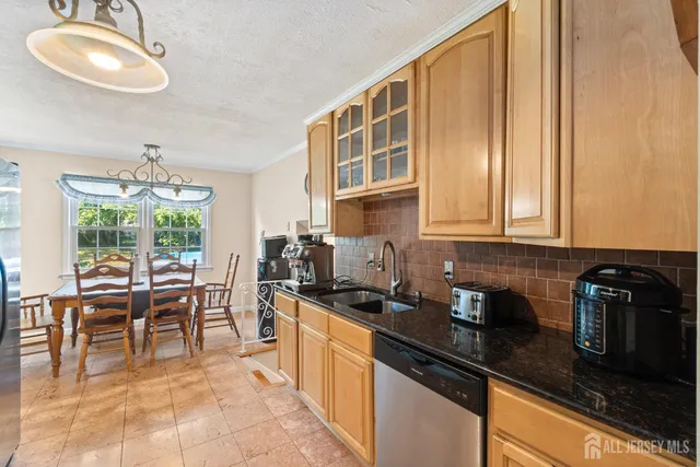 a kitchen with granite countertop a stove a sink a dining table and chairs with wooden floor