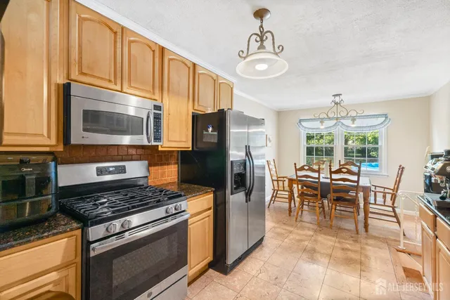 a kitchen with stainless steel appliances granite countertop a stove top oven a sink dishwasher a dining table and chairs with wooden floor