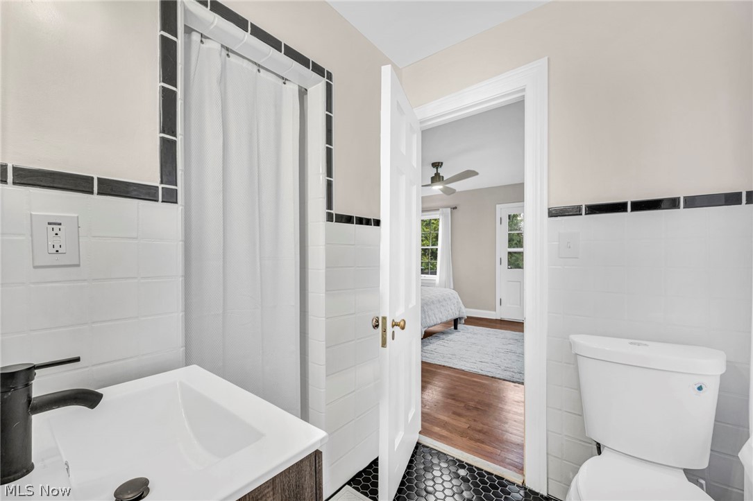 17409 Fernway Road Cleveland, OH 44120 - Photo 30 of 47 Bathroom with tile walls, hardwood / wood-style flooring, ceiling fan, and toilet