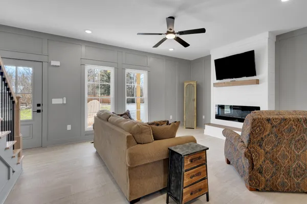 a living room with furniture a ceiling fan and a flat screen tv