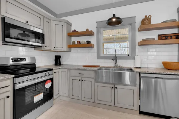 a kitchen with stainless steel appliances granite countertop a sink a stove and microwave