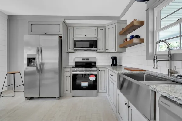 a kitchen with stainless steel appliances granite countertop a refrigerator a sink a stove and island