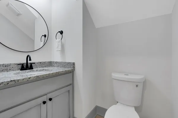 a bathroom with a granite countertop toilet sink and mirror