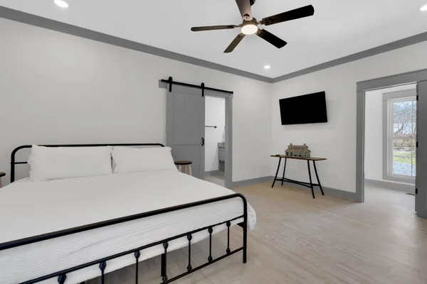 a bedroom with a bed a flat screen tv and a chandelier