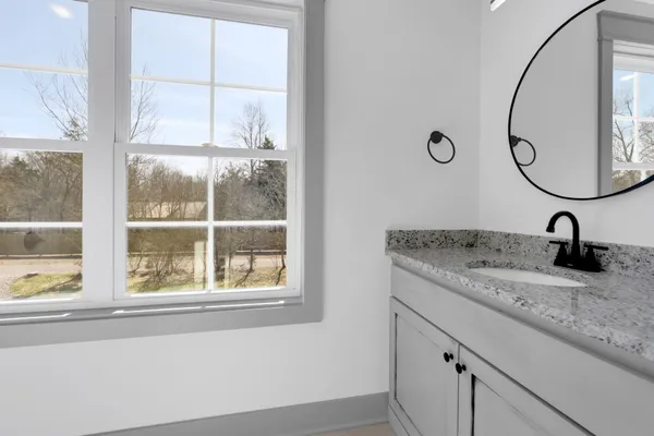 a bathroom with a granite countertop sink and a window