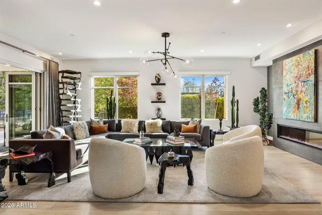 a living room with furniture large windows and wooden floor