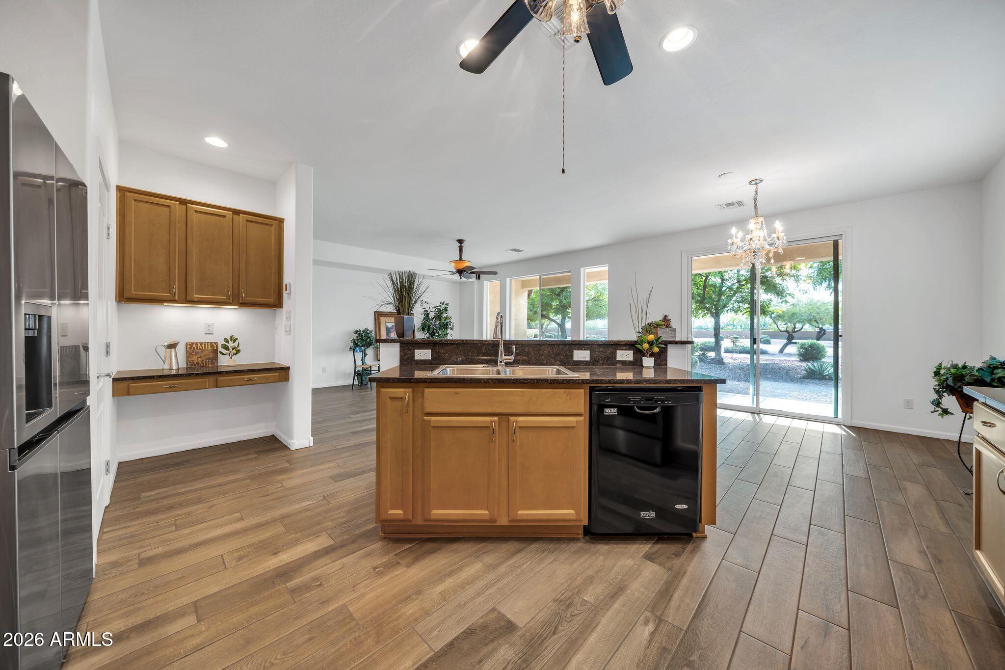16435 West Berkeley Road Goodyear, AZ 85395 - Photo 7 of 52 a kitchen with stainless steel appliances a stove a sink dishwasher a refrigerator and a dining table with wooden floor