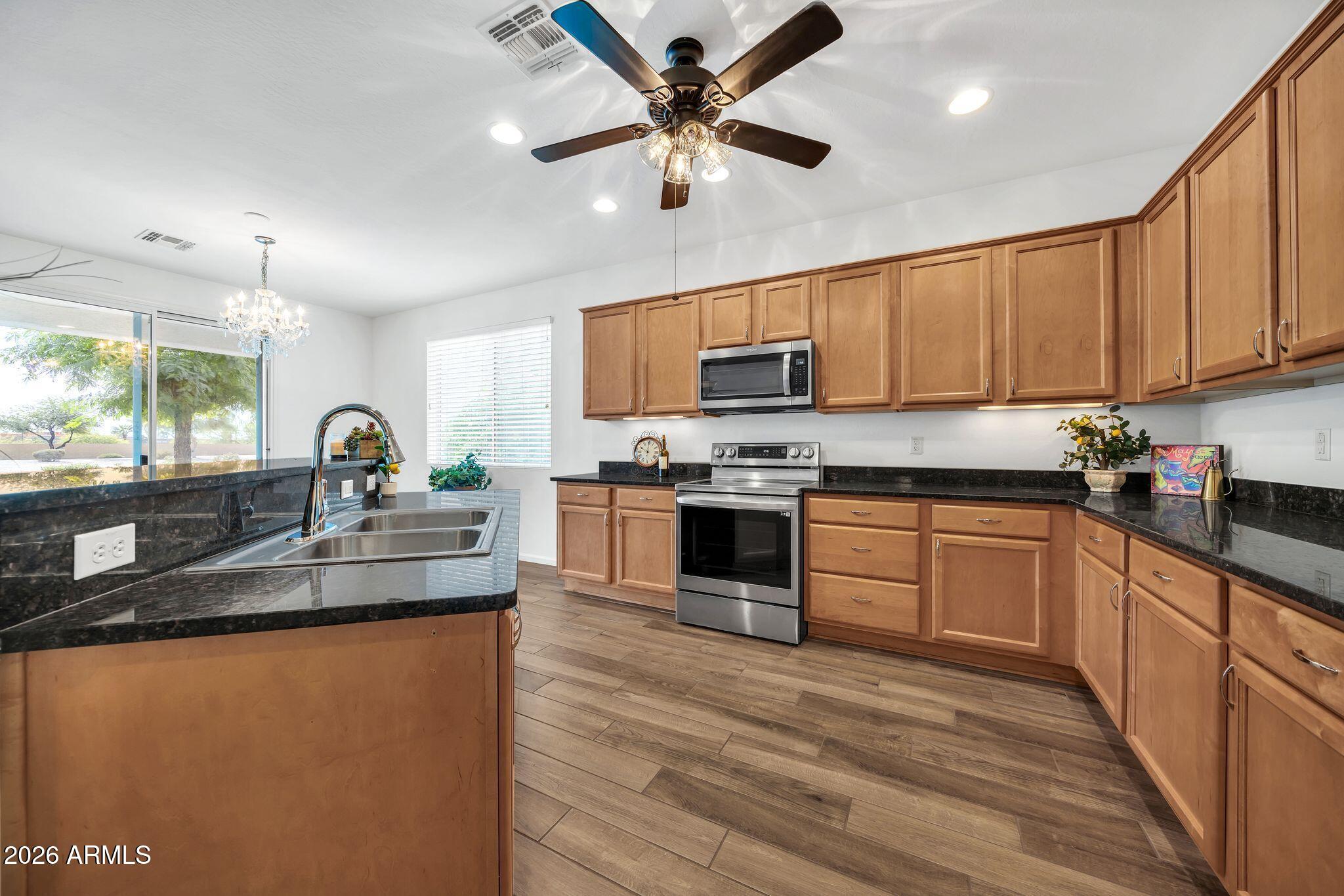 16435 West Berkeley Road Goodyear, AZ 85395 - Photo 8 of 52 a kitchen with stainless steel appliances granite countertop a sink a stove and a refrigerator