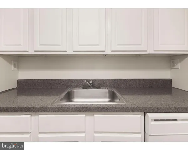 a kitchen with granite countertop white cabinets and a sink