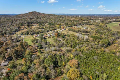 an aerial view of residential house with outdoor space and trees all around