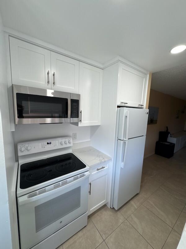 353 Highway 1, Unit A203 Jupiter, FL 33477 - Photo 15 of 26 a kitchen with white cabinets and stainless steel appliances