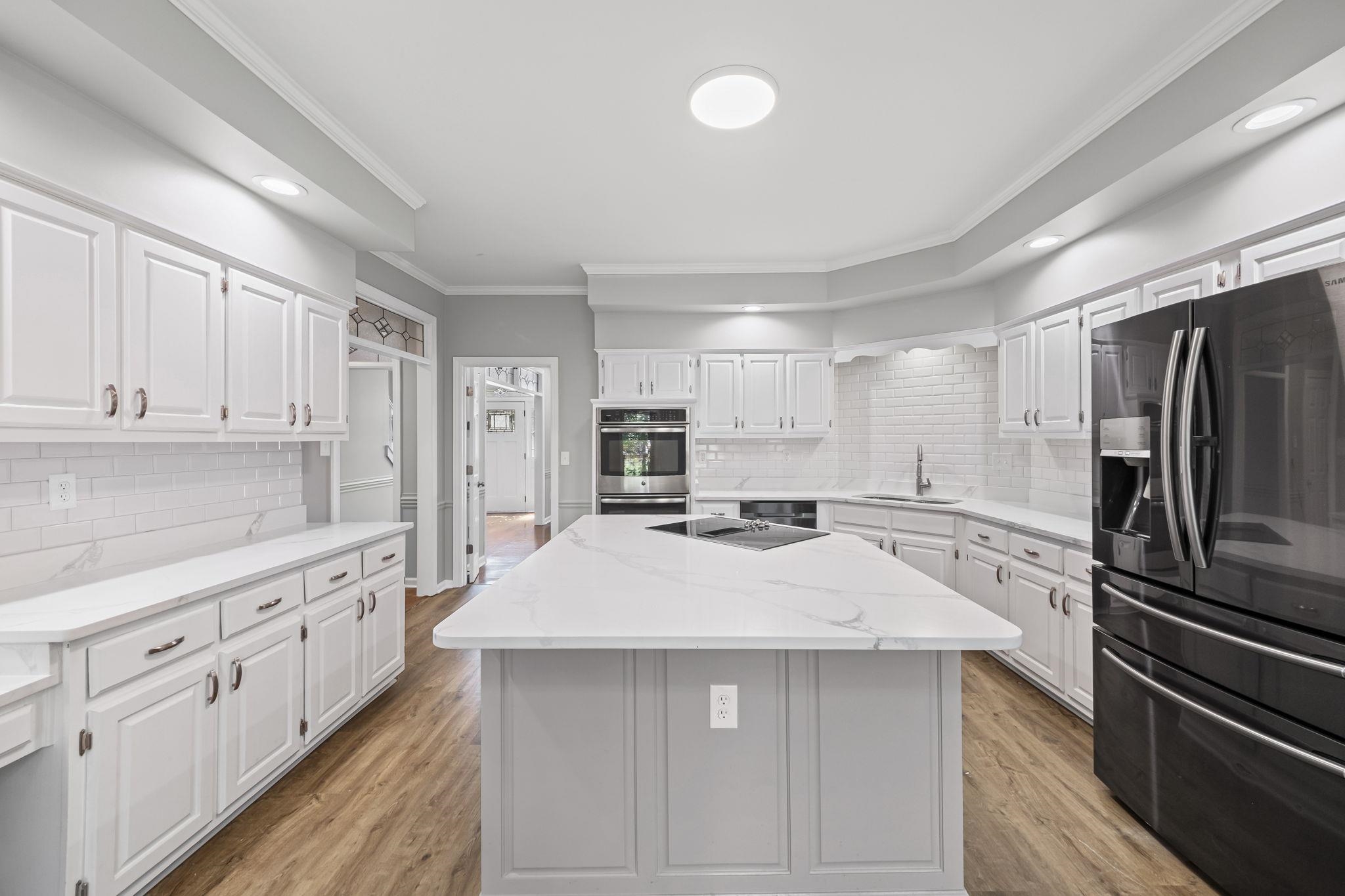 9190 East Bridge Drive Germantown, TN 38139 - Photo 11 of 37 Kitchen featuring crown molding, fridge with ice dispenser, decorative backsplash, light wood finished floors, and white cabinetry