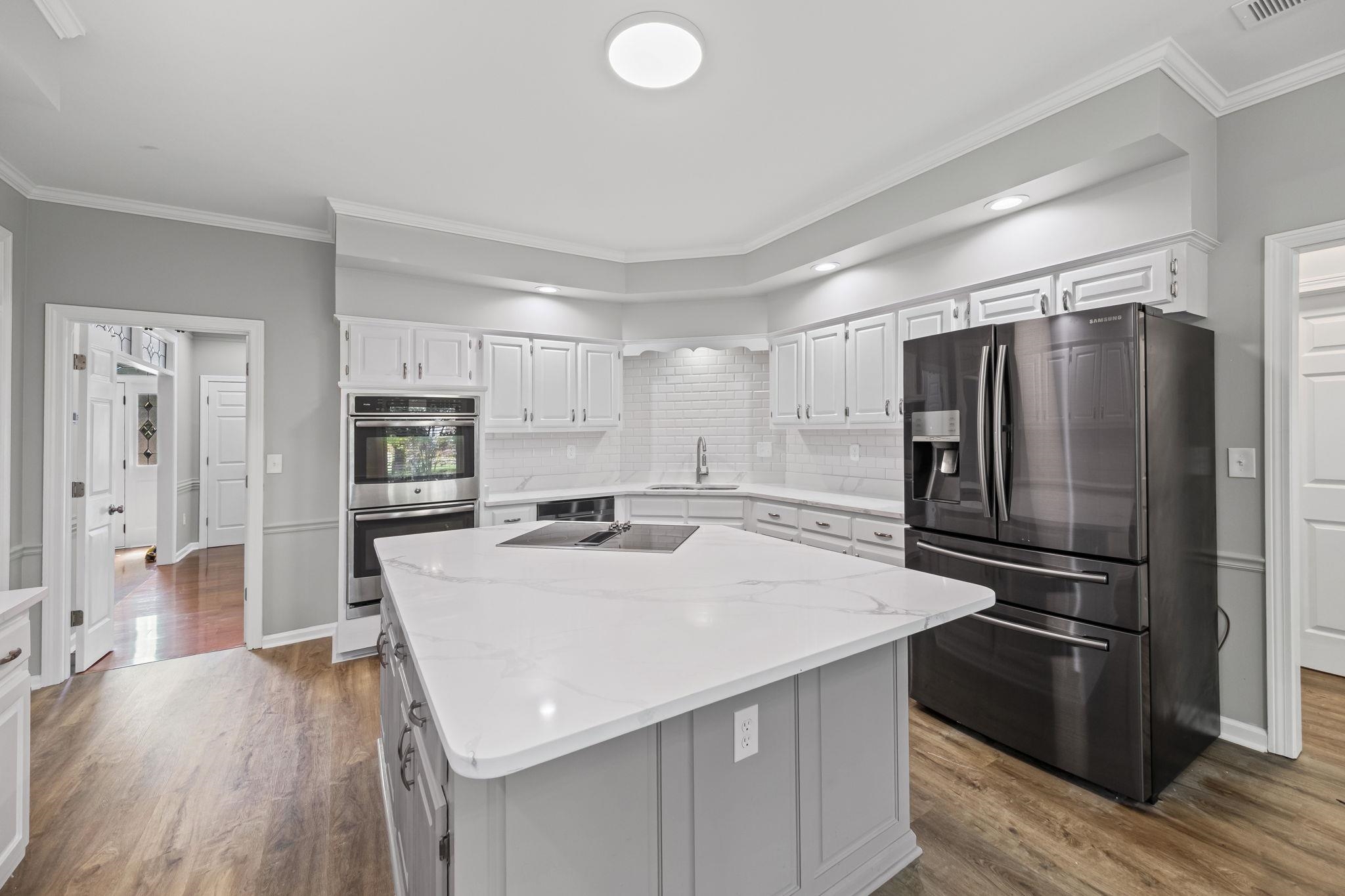 9190 East Bridge Drive Germantown, TN 38139 - Photo 12 of 37 Kitchen featuring crown molding, stainless steel appliances, white cabinetry, tasteful backsplash, and dark wood-style flooring
