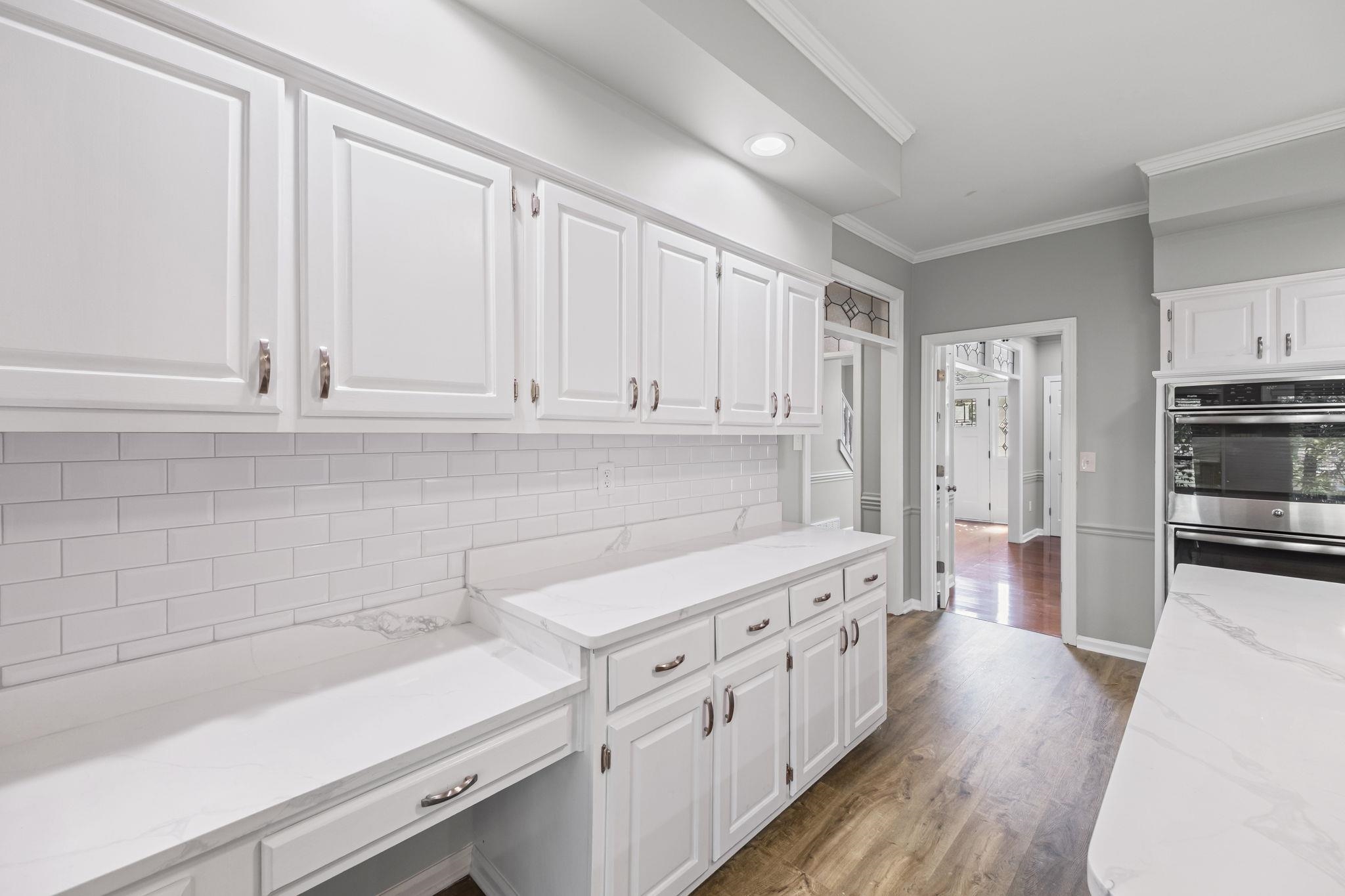 9190 East Bridge Drive Germantown, TN 38139 - Photo 14 of 37 Kitchen featuring tasteful backsplash, ornamental molding, light stone countertops, dark wood finished floors, and white cabinetry