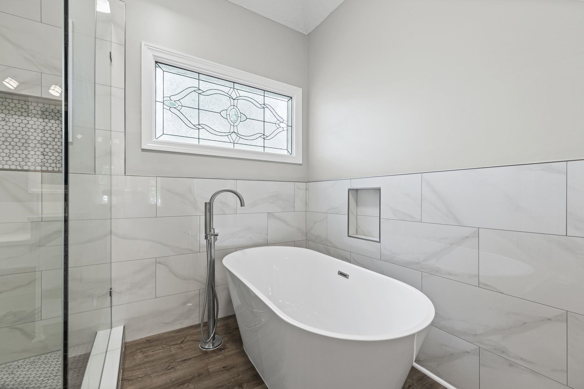 9190 East Bridge Drive Germantown, TN 38139 - Photo 25 of 37 Bathroom with tile walls, a soaking tub, wainscoting, dark wood-type flooring, and a tile shower