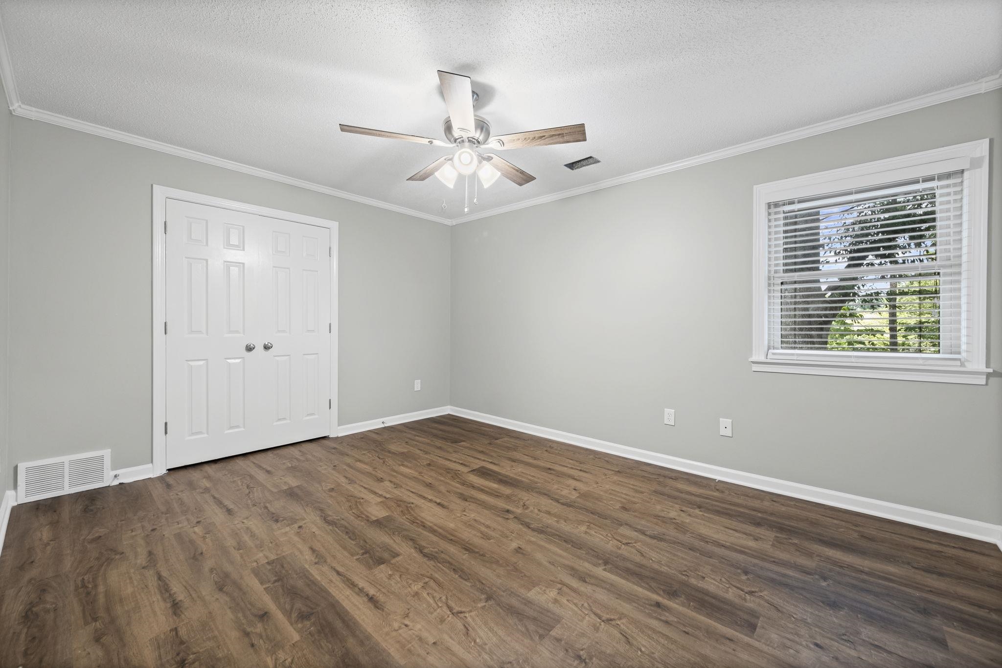 9190 East Bridge Drive Germantown, TN 38139 - Photo 27 of 37 Unfurnished bedroom with crown molding, dark wood finished floors, a textured ceiling, a ceiling fan, and a closet