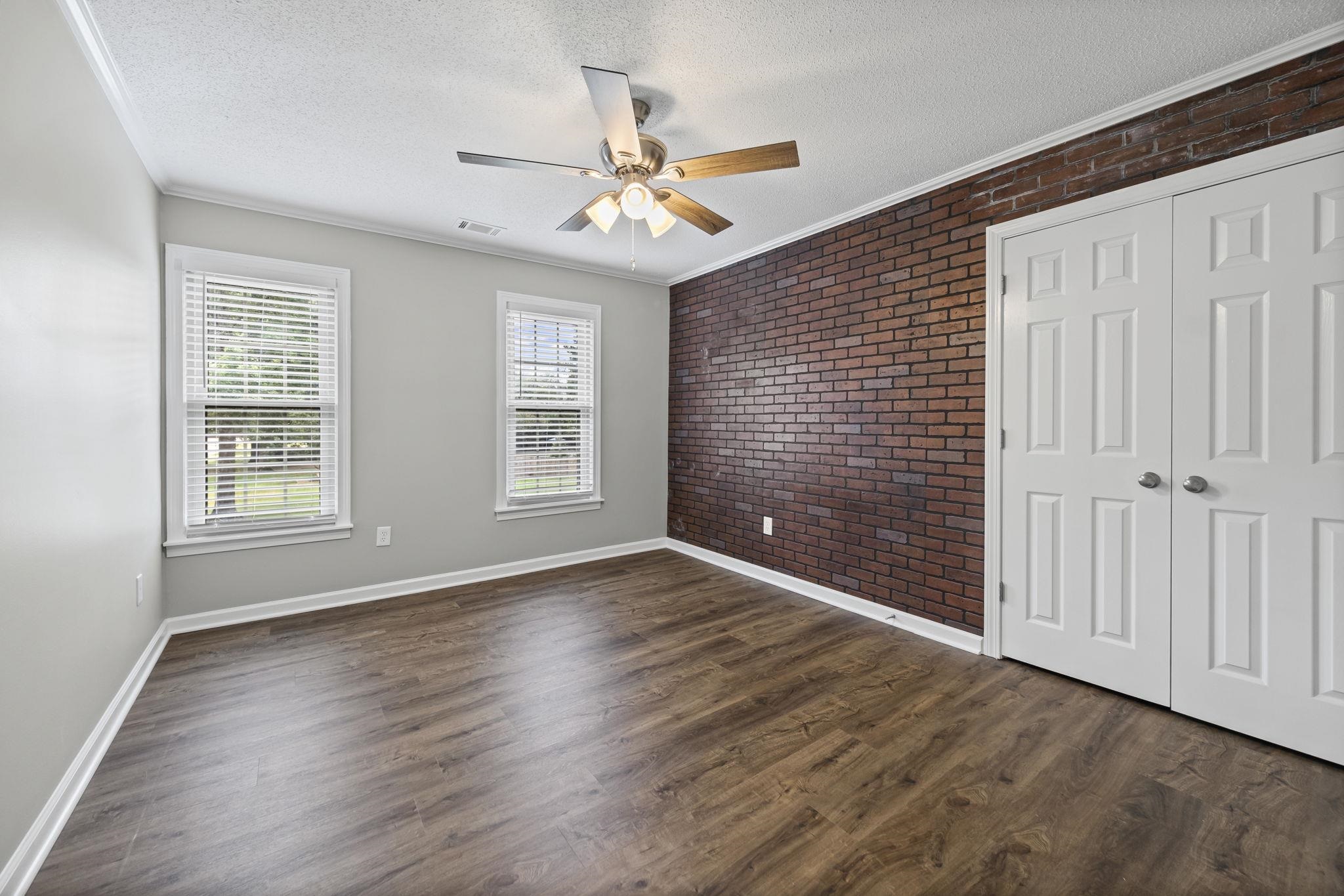 9190 East Bridge Drive Germantown, TN 38139 - Photo 28 of 37 Unfurnished bedroom with brick wall, crown molding, a textured ceiling, a closet, and dark wood-type flooring