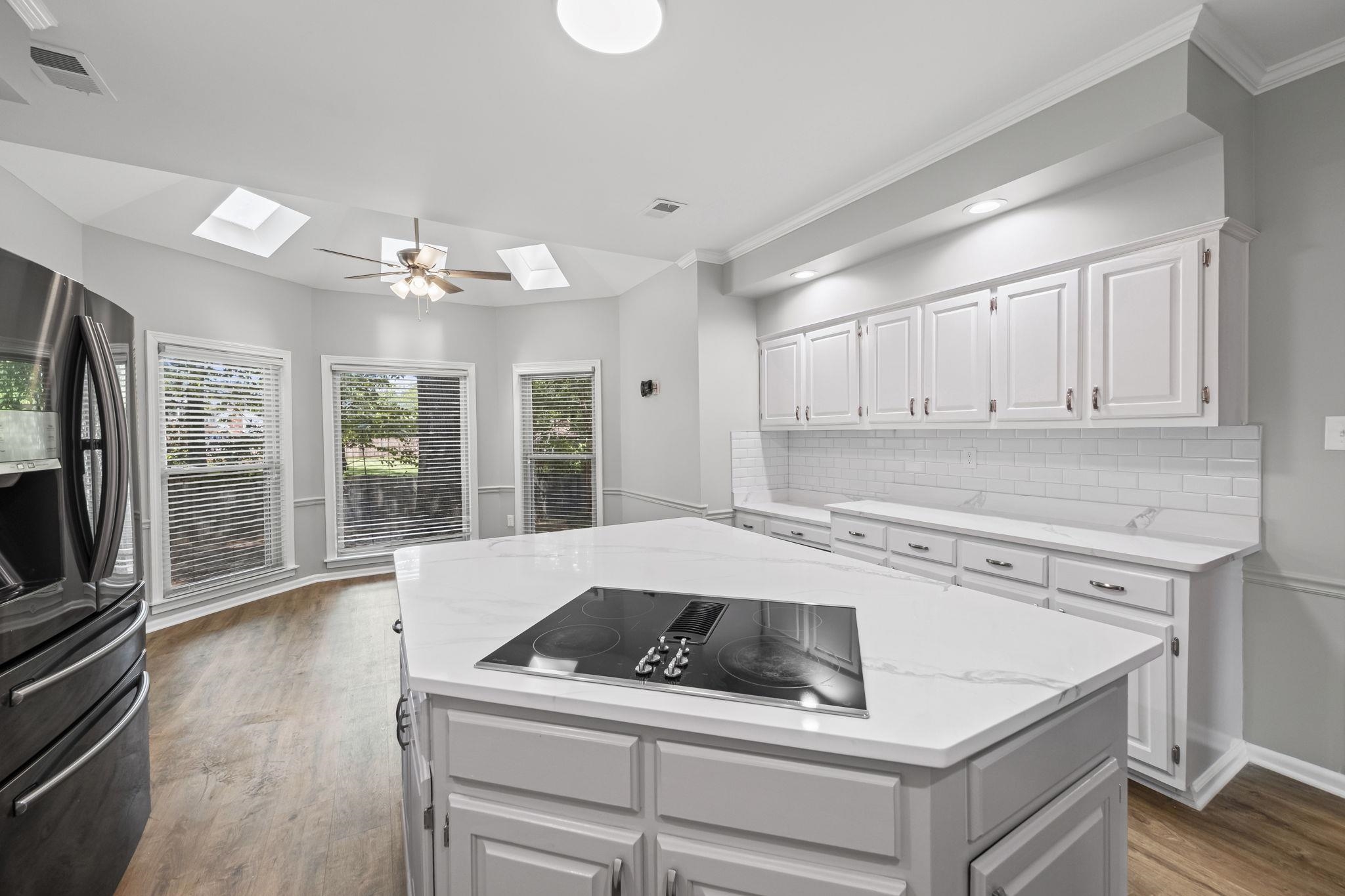 9190 East Bridge Drive Germantown, TN 38139 - Photo 10 of 37 Kitchen with backsplash, stainless steel fridge with ice dispenser, white cabinets, dark wood finished floors, and light stone countertops