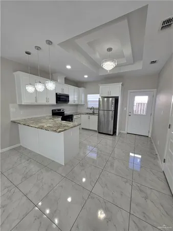 a large kitchen with granite countertop a stove a sink a counter space and cabinets