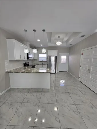 a large kitchen with granite countertop a large counter top and stainless steel appliances