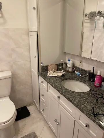 a bathroom with a granite countertop sink a toilet and a mirror