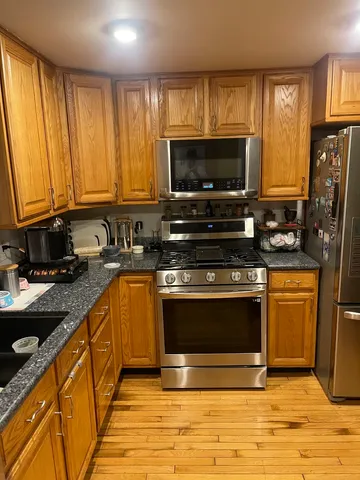 a kitchen with stainless steel appliances granite countertop a stove a sink and a microwave