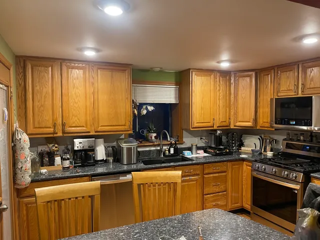 a kitchen with stainless steel appliances a sink a stove a refrigerator cabinets and a window