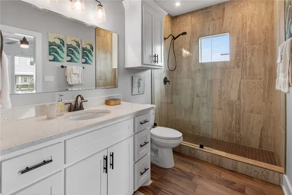 a bathroom with a granite countertop sink toilet a mirror a vanity and shower