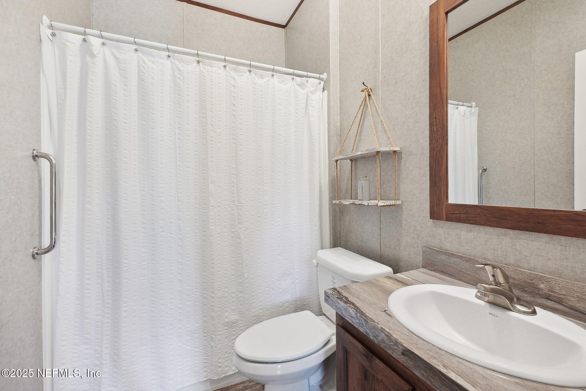 8145 Colee Cove Road St. Augustine, FL 32092 - Photo 24 of 35 a bathroom with a sink a toilet and shower curtain